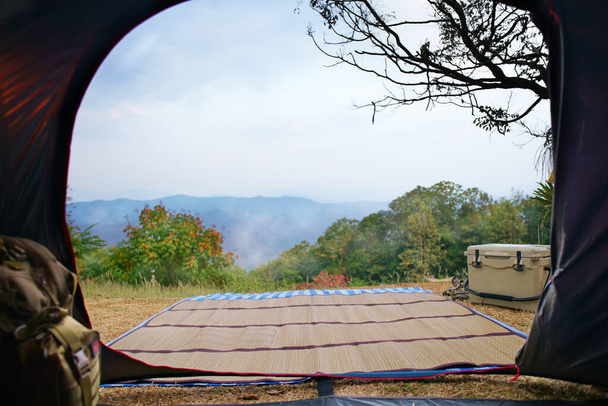 natura namiot kempingowy z gałęzią drzewa na trawie i zielonej górze z chłodniejszym polu i plecakiem sos w parku narodowym lasu z mgłą na błękitnym niebie na wakacje piknik na wakacje relaks podróży rano - Zdjęcie, obraz