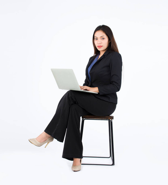 Asian Businesswoman using a laptop while sitting on a chair. A working woman sat with her legs crossed confidently. - Foto, imagen