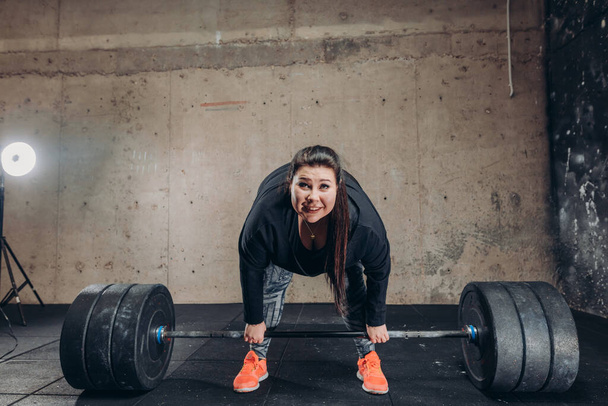 plump woman cannot lift the barbell at fitness center - 写真・画像