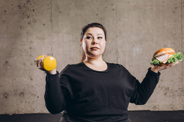 plump woman chosing sport or junk food - Fotografie, Obrázek