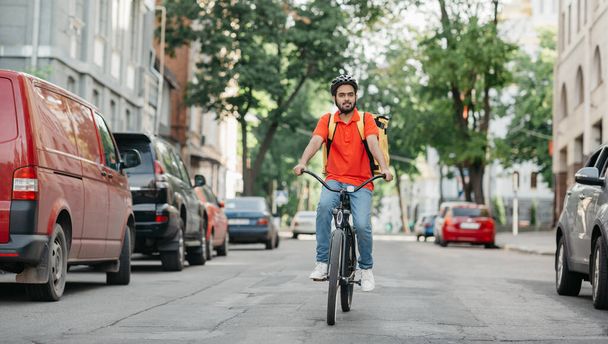 Servicio de entrega urgente. Ciclista con casco y mochila amarilla paseos por carretera - Foto, imagen