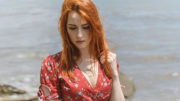 Redhead woman in dress enjoys a walking near the sea shore. - Fotografie, Obrázek