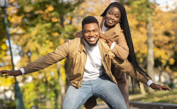 Happy afro couple having fun on date in autumn park - Фото, зображення