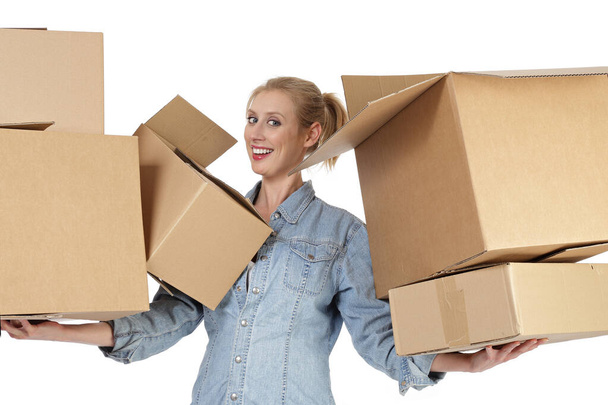 šťastný mladý a pěkný kavkazský blondýnka žena úsměv pohybující se s kartónovými krabicemi na bílém izolovaném pozadí - Fotografie, Obrázek