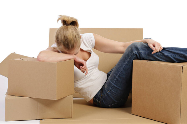 виснажена молода і досить біла блондинка рухається з картонними коробками на білому ізольованому фоні
 - Фото, зображення