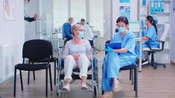 Krankenschwester macht Notizen von behinderter Seniorin - Filmmaterial, Video