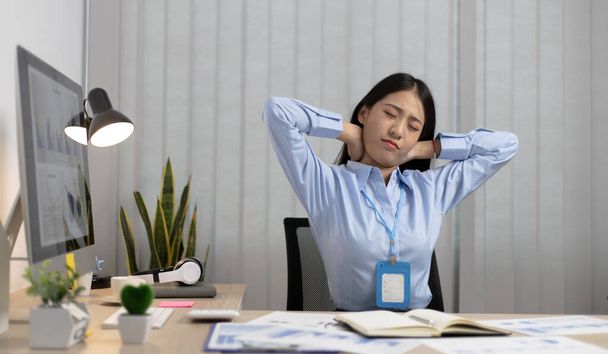 Азиатская деловая женщина расслабляется после сверхурочной работы в офисе, Счастливые женщины отдыхают на работе после работы. - Фото, изображение