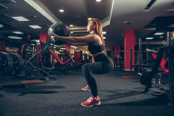 Young muscular caucasian woman practicing in gym with equipment. Wellness, healthy lifestyle, bodybuilding. - Photo, image