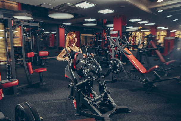 Young muscular caucasian woman practicing in gym with equipment. Wellness, healthy lifestyle, bodybuilding. - Fotó, kép