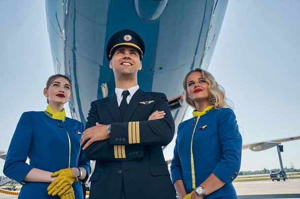 Zwei schöne Stewardessen und ein Flieger, der voraus starrt - Foto, Bild