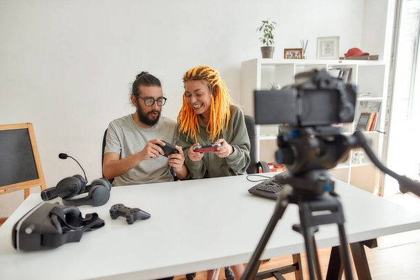 Man and woman using, discussing game controller joystick. Young male and female technology blogger recording video blog or vlog about new gadgets at home - Foto, afbeelding