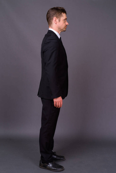 Студійний знімок гарного бородатого бізнесмена в костюмі на сірому фоні
 - Фото, зображення