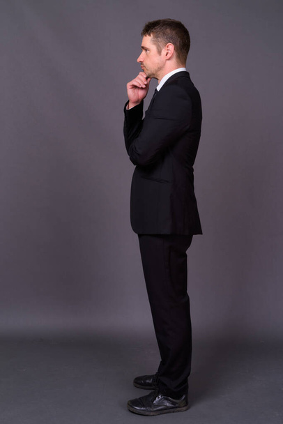 Studio shot of handsome bearded businessman in suit against gray background - 写真・画像