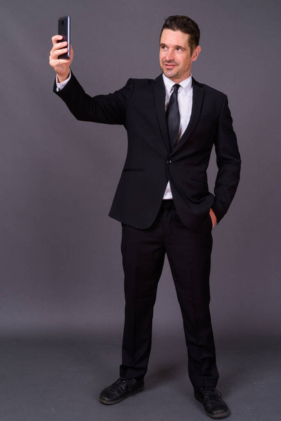 Studioaufnahme eines gutaussehenden bärtigen Geschäftsmannes im Anzug vor grauem Hintergrund - Foto, Bild
