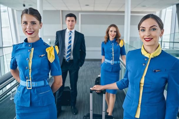 Удовлетворенные сотрудники авиакомпании, стоящие в здании аэропорта - Фото, изображение