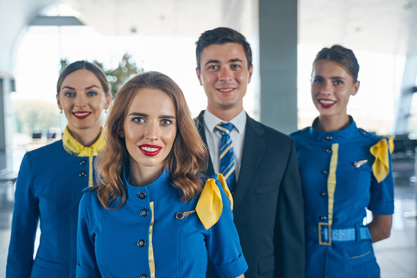Handsome steward and female flight attendants looking forward - Foto, imagen
