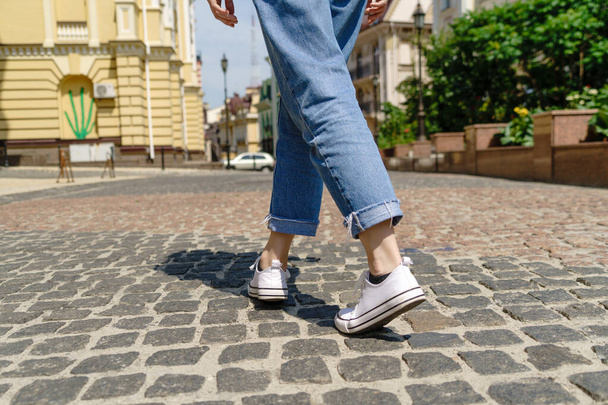 Close up of person walking on paving stone street at summer day - Фото, изображение