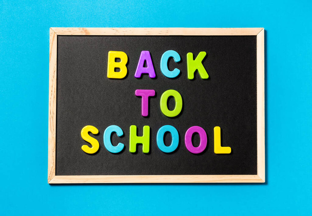 The concept of going back to school. Back to school in colored letters on a chalkboard on a blue background. Space for text. The view from the top - Foto, Imagem