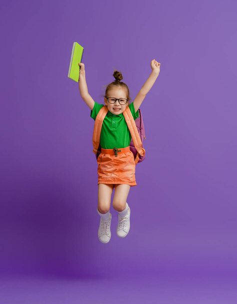 Back to school and happy time! Cute industrious child on color paper wall background. Kid with backpack. Girl ready to study. - Foto, Imagem