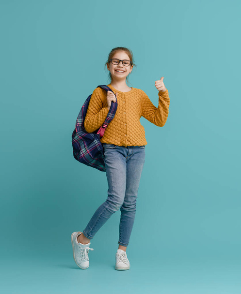 Back to school and happy time! Cute industrious child on color paper wall background. Kid with backpack. Girl ready to study. - Photo, Image