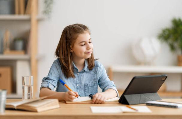 Back to school. Happy child is sitting at desk. Girl doing homework or online education. - Foto, afbeelding