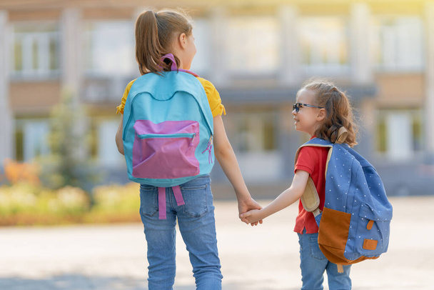 Pupils of primary school. Girls with backpacks outdoors. Beginning of lessons. First day of fall.     - Φωτογραφία, εικόνα