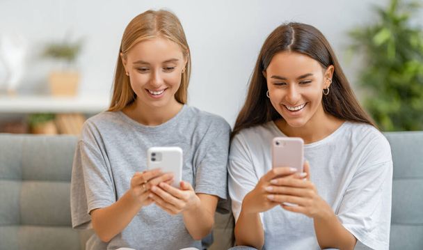 Young women are using phones. Funny girls having fun staying at home. - Foto, Bild