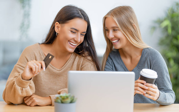 Two happy young women doing online purchases. Girls doing shopping at home. - Φωτογραφία, εικόνα