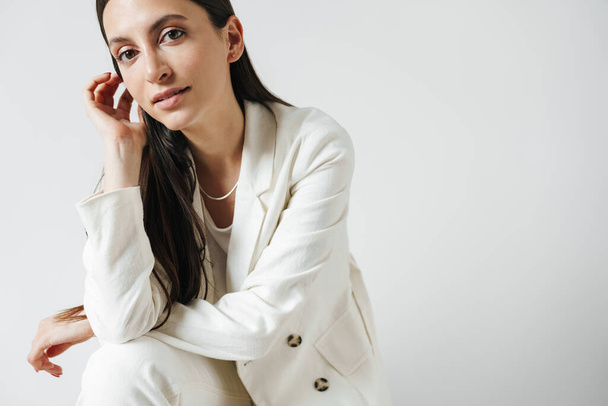 Photo of confident businesswoman in jacket posing and looking at camera isolated over white background - Fotó, kép