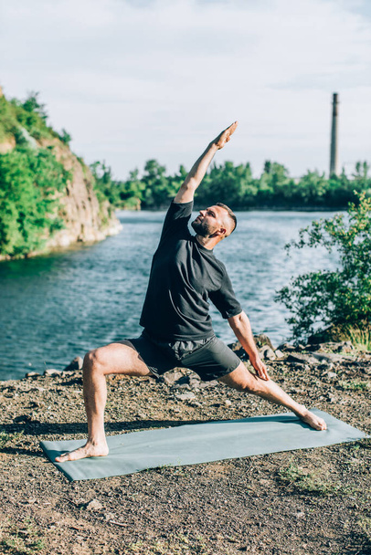 Een man die yoga-oefeningen doet op het groeve meer op zonnige dag. Internationale Yoga-dag. - Foto, afbeelding
