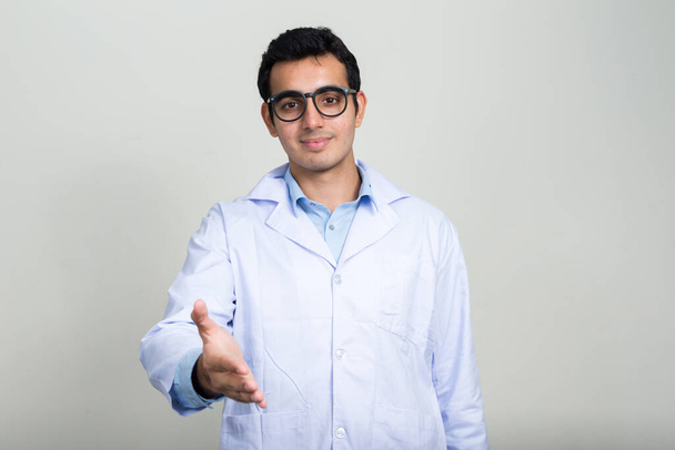 Studio shot of young handsome Indian man doctor against white background - Foto, imagen