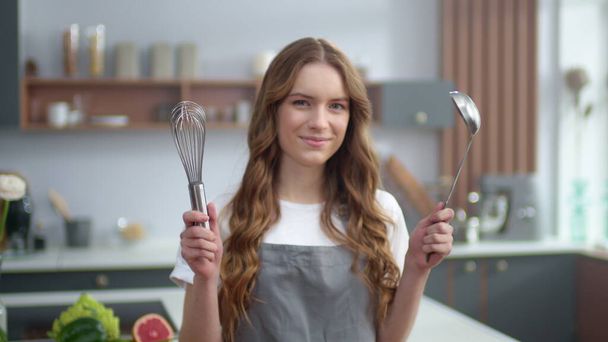 Kokki nainen valmistautuu ruoanlaittoon keittiössä. Kotiäidin muotokuva keittiövälineillä
 - Valokuva, kuva