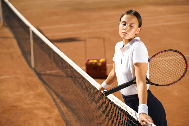 Красивая девушка с ракеткой позирует на теннисном корте - Фото, изображение