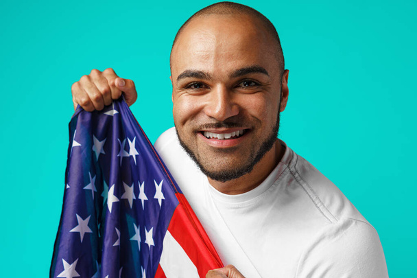 Portrait of young dark-skinned man proudly holding USA flag - Zdjęcie, obraz