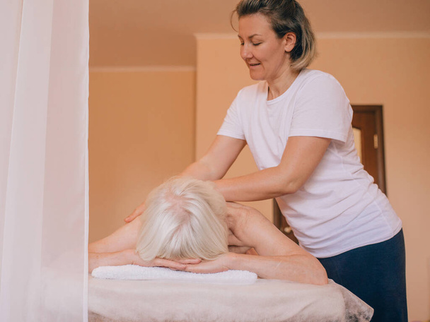 Літня (стара) кавказька стильна жінка з сивим волоссям лежить на масажі. Антивік, здоровий спосіб життя, масаж концепції - Фото, зображення