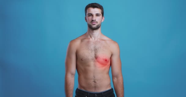 Nuori paidaton mies, jolla on sykkivä punainen täplä rinnassa, sydänsairaus - Materiaali, video