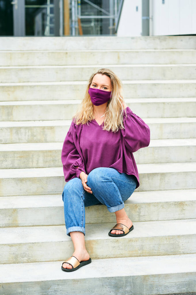 Retrato de moda al aire libre de mujer bonita con blusa púrpura y mascarilla - Foto, Imagen