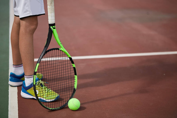 Κοντινό πλάνο του αρσενικού χεριού κρατώντας μπάλα του τένις και ρακέτα στο γήπεδο κόκκινο πηλό. - Φωτογραφία, εικόνα