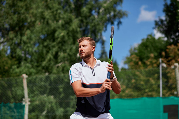 Young man in sportwear is playing tennis on out door court. - Fotoğraf, Görsel