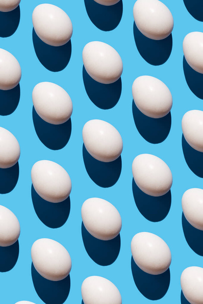 Pattern made of eggs on pastel blue background. Minimal food concept.Flatlay of trendy seamless pattern eggs. - Foto, imagen