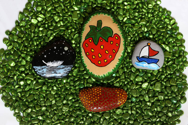 Beautifully painted stones lie on green stones. - Photo, Image