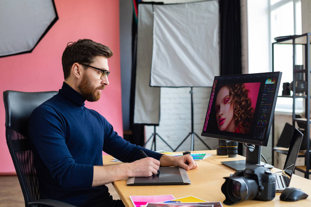 Retouching images in special program.Portrait of graphic designer working in office with laptop,monitor,graphic drawing tablet and color palette.Retoucher workplace in photo studio.Creative agency - Φωτογραφία, εικόνα
