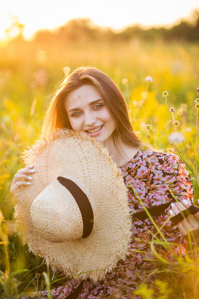 young beautiful european girl in the setting sun, on the field,in hat - Φωτογραφία, εικόνα