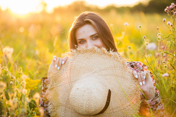 young beautiful european girl in the setting sun, on the field,in hat - Fotografie, Obrázek