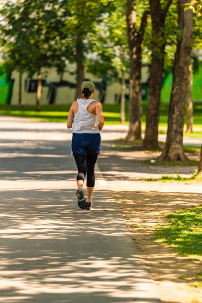 Грац, Штирия, Австрия - 24.06.2020: вид на молодую женщину, бегающую по дорожке в парке - Фото, изображение