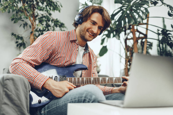 Man playing electric guitar and recording music into laptop - Fotoğraf, Görsel