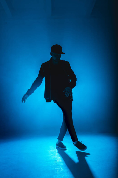 Professional male dancer dancing in night club with smoke and blue neon lights - Фото, зображення