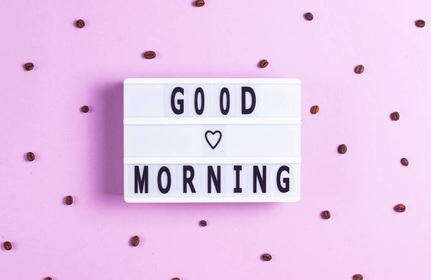 Напис Доброго ранку на білій дошці на рожевому фоні з кавовими зернами
 - Фото, зображення