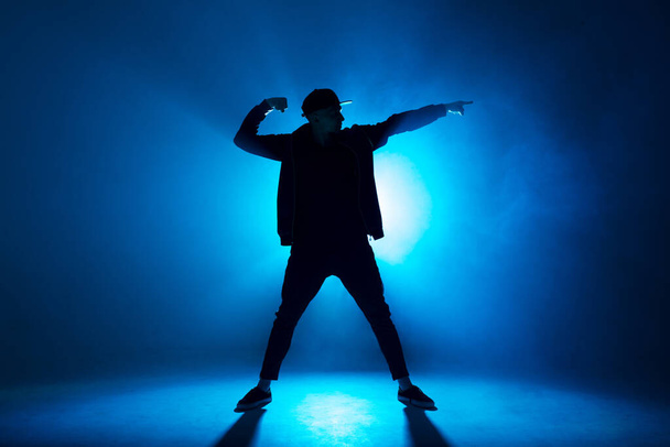 Professional male dancer dancing in night club with smoke and blue neon lights - Фото, зображення