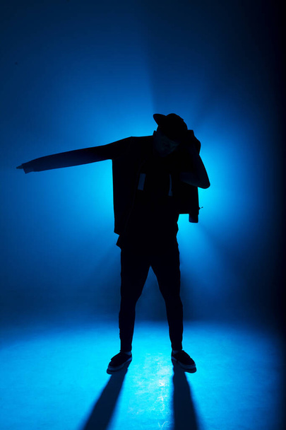 silhouette of male dancer isolated on blue neon background with flare in middle - Photo, image